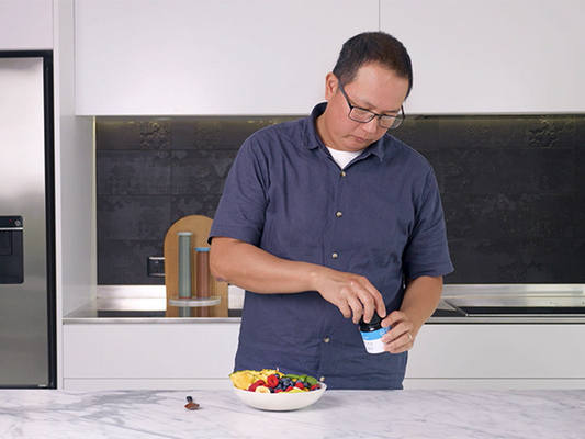 Person preparing a bowl of fruit in a modern kitchen.