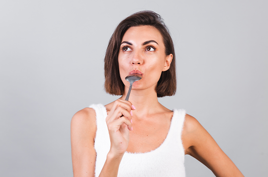 Woman thinking with a fork in her mouth, looking contemplative.