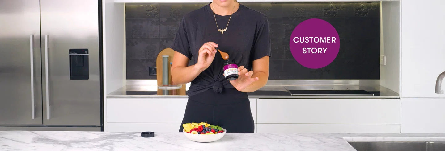 Person in black shirt holding supplement jar in modern kitchen with colorful salad bowl on marble counter