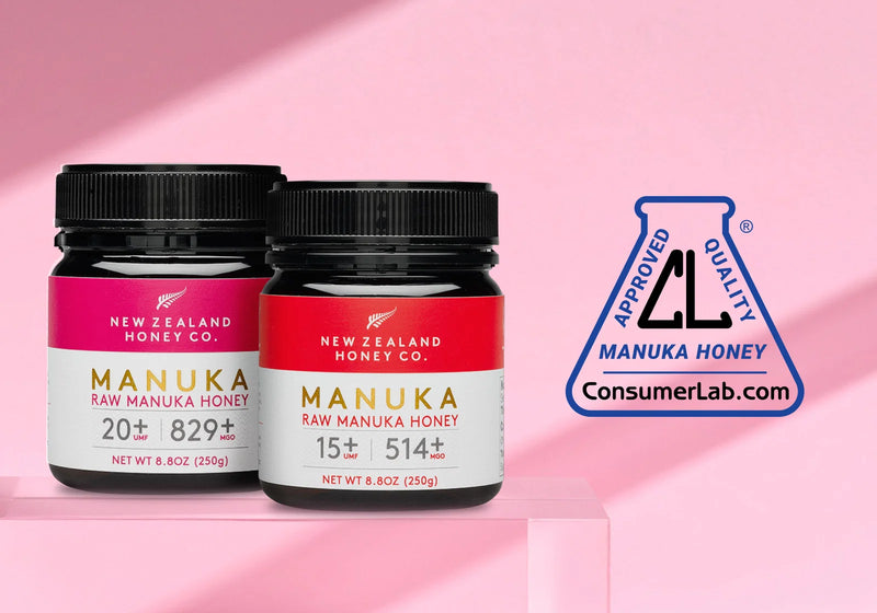 Two jars of New Zealand Honey Co. Manuka honey with black lids and red/pink labels on a pink background with ConsumerLab approval badge.