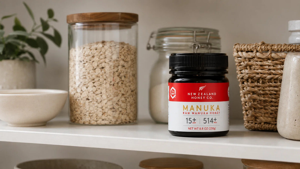 New Zealand Manuka honey jar displayed on a shelf with oats, baskets, and kitchen items