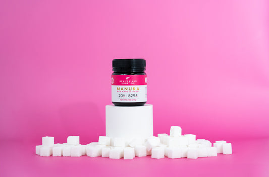 Container of product on a pedestal with sugar cubes, against a pink background.