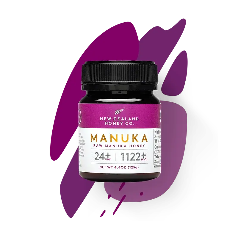 New Zealand Honey Co. Manuka Honey Mini jar UMF™ 24+ MGO 1122+ (purple label) on a purple paint-splash studio background, 125g (4.4oz)