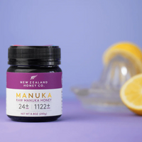 New Zealand Honey Co. Manuka Honey UMF™ 24+ jar styled with sliced lemon and a juicer on a lavender background