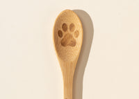 Close-up top-down view of the bamboo paw-print spoon included with New Zealand Honey Co. Pet Manuka Honey