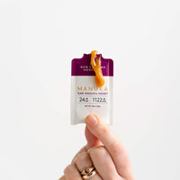 Close-up of a hand holding a New Zealand Honey Co. Manuka Honey on-the-go sachet UMF™ 24+ MGO 1122+ with honey extruded from the top, 10g (0.35oz)