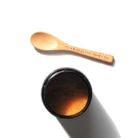 Top-down view of an open Manuka honey jar showing the golden surface, paired with a New Zealand Honey Co. bamboo Daily Spoon